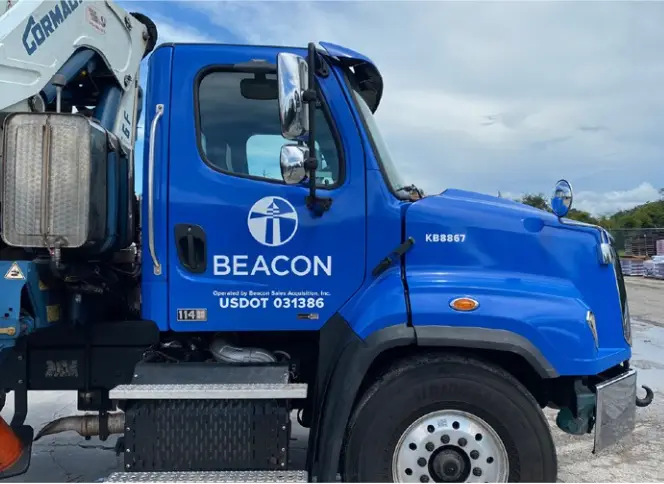 Blue Beacon Building Products truck with branded logo wrap and USDOT markings, parked at a jobsite featuring brand decals