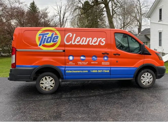 Orange Tide Cleaners delivery van with branded wrap promoting dry cleaning, free pickup and delivery, and rewards program.