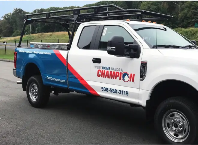 Champion Windows branded work truck with ladder rack, featuring a partial vehicle wrap advertising home improvement services and local contact number.